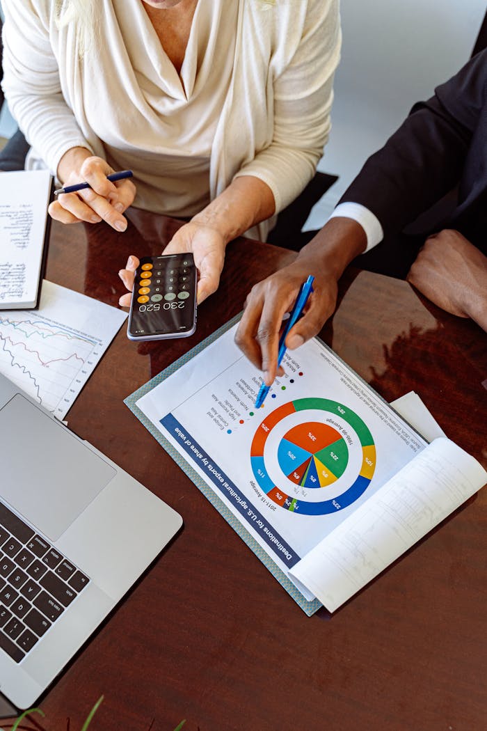 Two business professionals discussing financial documents and strategies at an office desk.